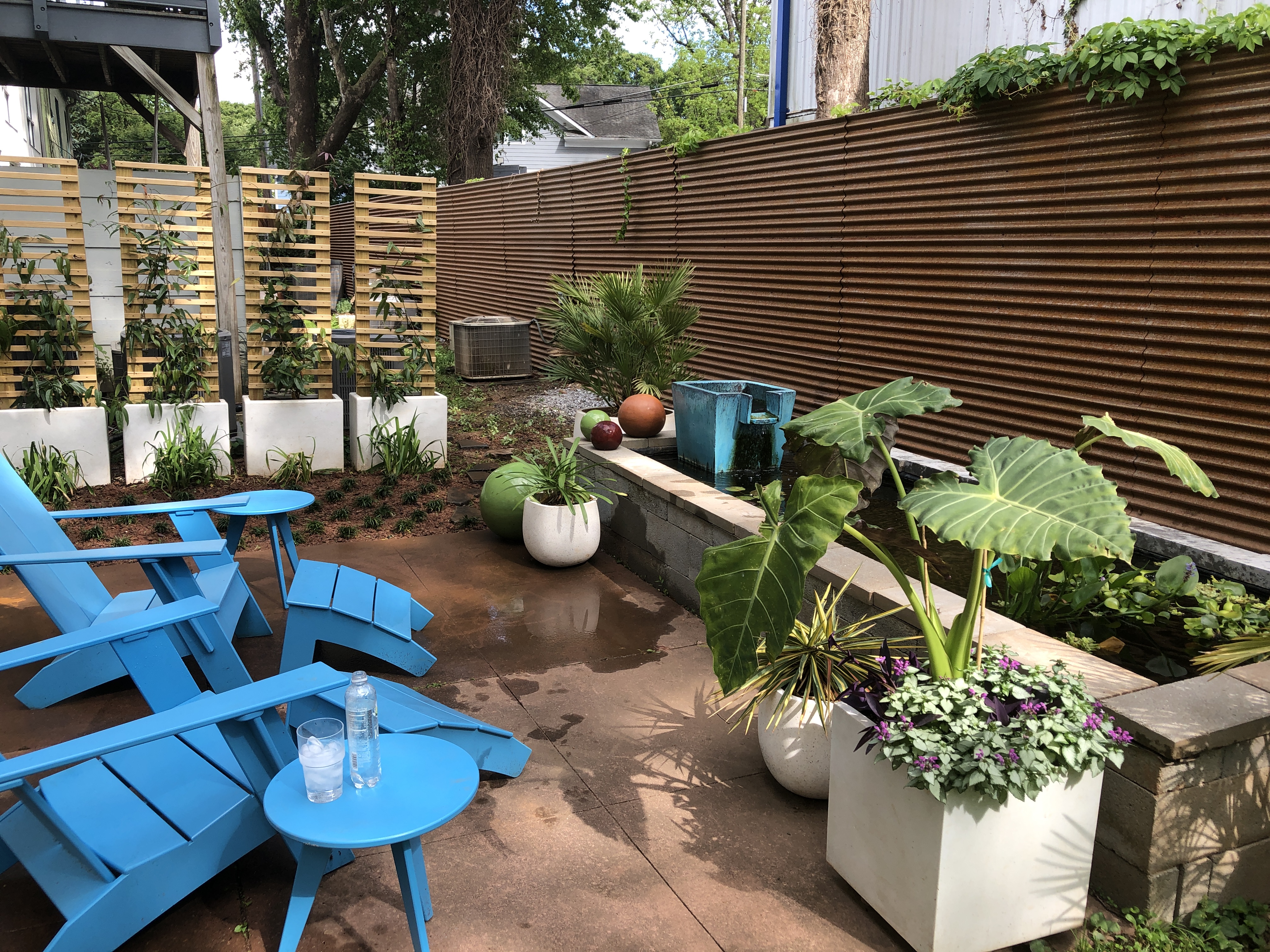 A small outdoor seating area with blue chairs and potted plants.