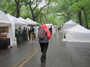 Rainy inman park festival day with solitary walker bundled up in front of zipped up artist tents
