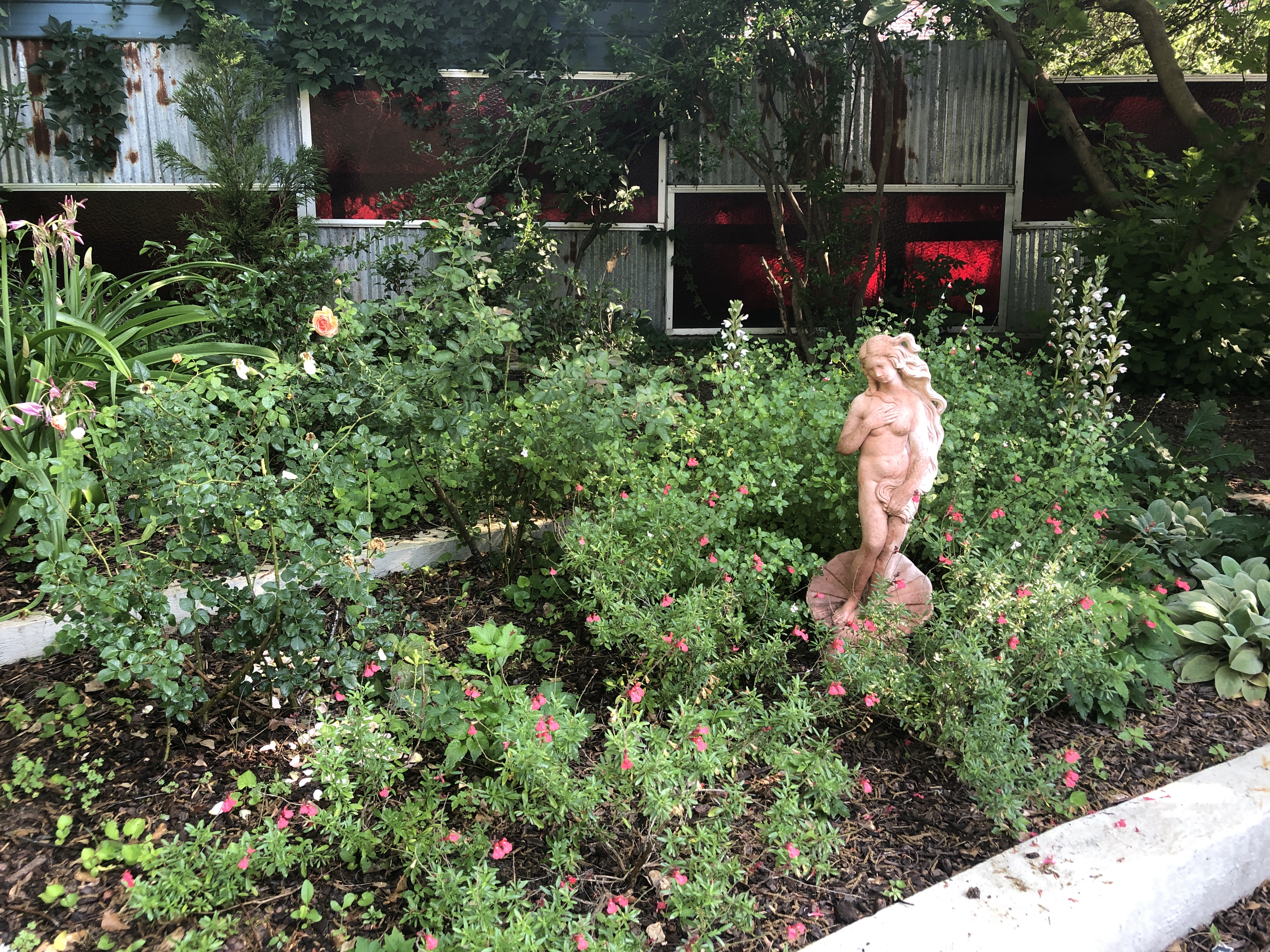 a garden with a statue and flowers